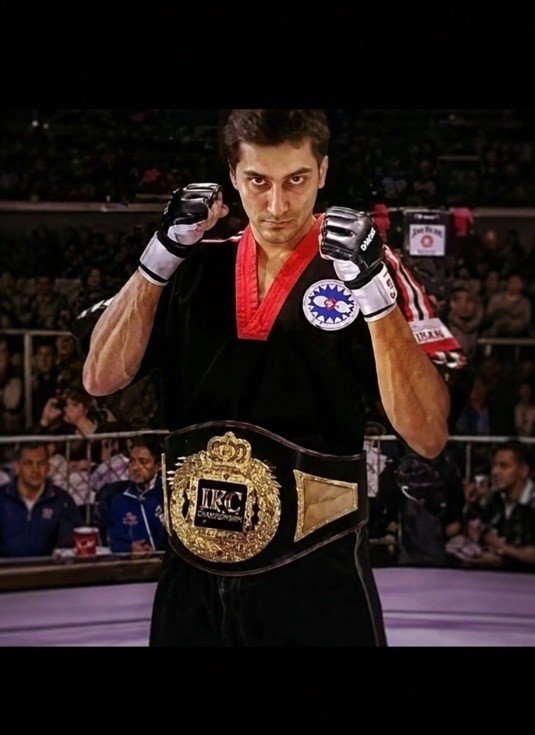 Mah Ghasemi in the ring holding his championship belt