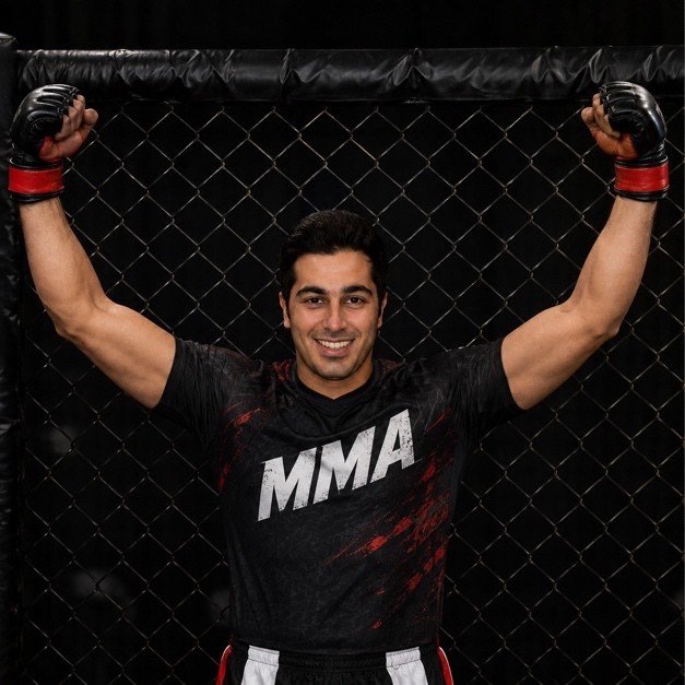 Mah Ghasemi in an MMA cage with his arms raised